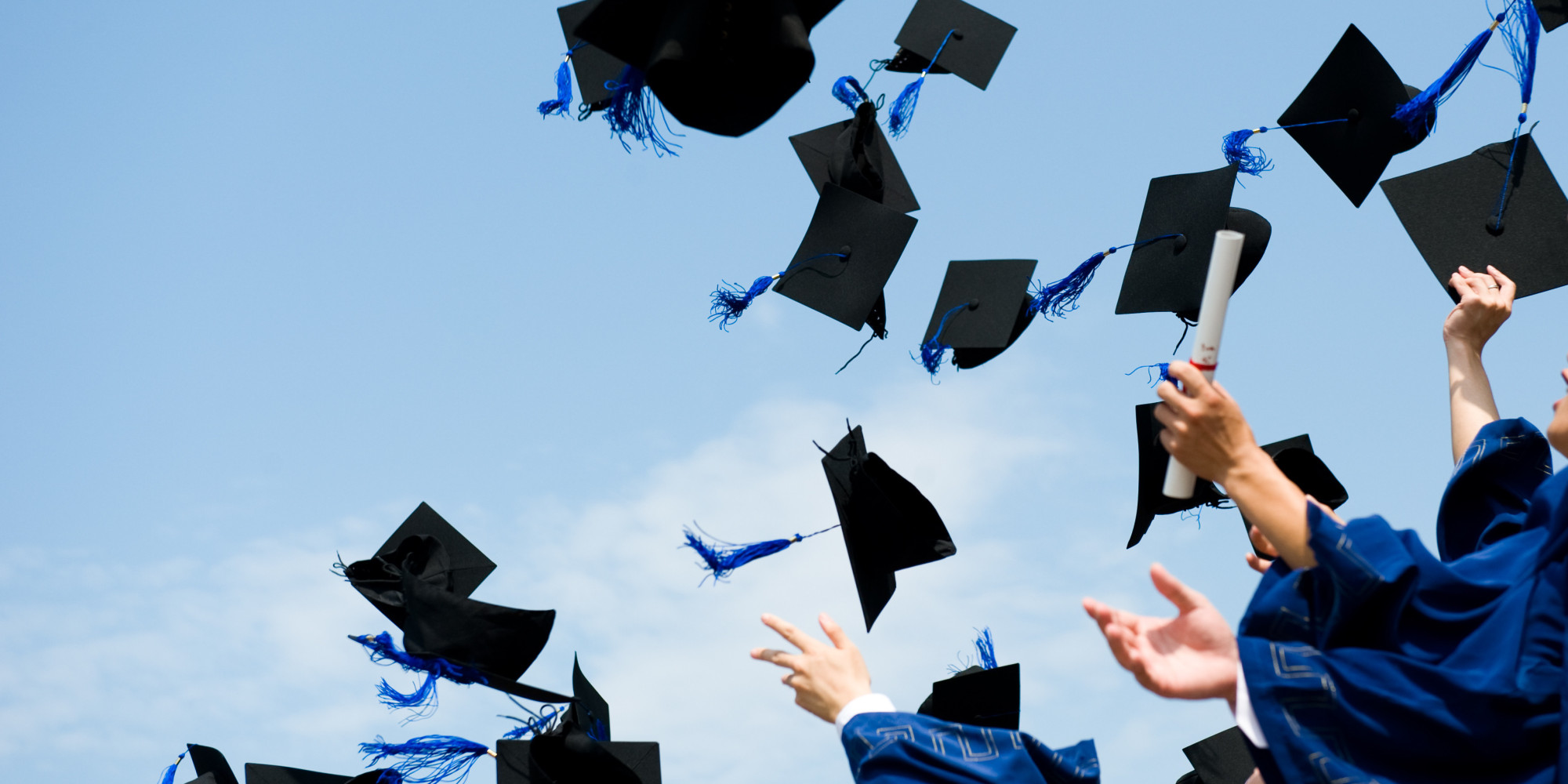 The hands of school graduates throwing their hats up into the sky.